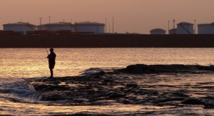 Fisherman Silhouted by setting sun beyond the Port Botany Fuel storage.